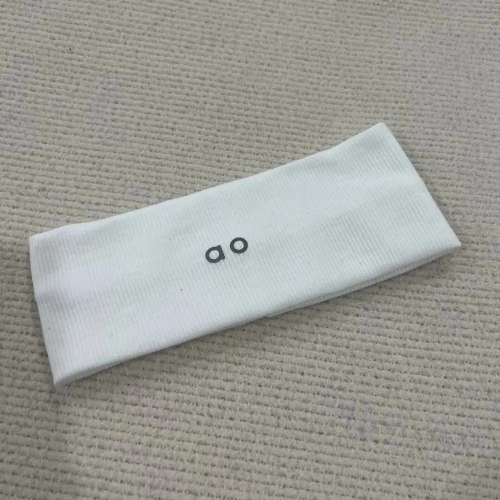 One white ribbed headband photographed on fabric on a verified product product page
